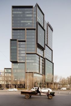 a man riding a skateboard down a street past a tall building with lots of windows