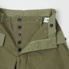 Based on the iconic USMC standard issue ‘monkey pant’, the 1097 from Warehouse & Co masterfully captures the original authentic feel of a military icon. Cut from a 100% cotton HBT fabric, this olive drab trouser is a loose fitting, high rise model which is luxuriously comfortable and obscenely functional. The softness of the cotton is met with heavy duty manufacturing techniques as illustrated by double felled seams on the inside and outer leg, reinforced custom branded buttons, and a crossover Dapper Outfit, Sewing Details, Army Pants, Comfortable Pants, 8 Ball, Utility Pants, Clothes Shopping, Clothing Co, Herringbone