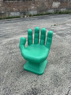 a green plastic hand sitting on top of a cement ground