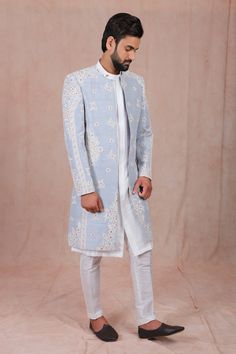 Maya blue sherwani with all-over floral embroidery, round neckline and full sleeves. Comes with high neck white kurta and mexican-style pant. Component: 3 Embroidered Neckline: Jacket: Round; Kurta: High Neck Sleeve Length: Full Fabric: Raw Silk Color: Blue Long sherwani Concealed placket - Aza Fashions Maya Blue, Indian Groom Dress, Blue Sherwani, Embroidered Sherwani, Groom Dress Men