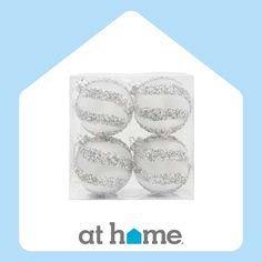 four white christmas baubles with silver glitters on them in a clear package