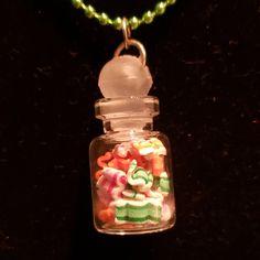 a glass jar with candy in it sitting on a table next to a beaded necklace