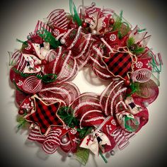 a red and white christmas wreath with decorations on it's front door hanger