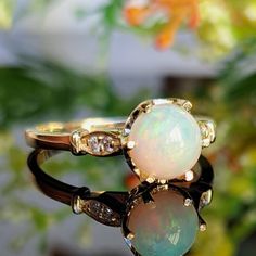 an opal and diamond ring sitting on top of a flower pot with leaves in the background