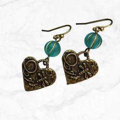 These delightful earrings feature bronze hearts and a heart charm with dragonfly dangling gracefully from aqua glass beads. The combination of earthy bronze tones and vibrant aqua creates a pretty coastal cowgirl look. Whether you're strolling along the beach or dancing under the stars, these earrings add a touch of whimsy and elegance to any outfit. Lightweight everyday earrings for casual or dressy occasions.  Artisan glass beads produced in small quantities in the Czech Republic Hypoallergeni Bronze Dangling Beads Earrings For Gift, Bronze Earrings With Dangling Beads For Gift, Gift Bronze Beaded Earrings, Adjustable Bronze Beaded Earrings As Gift, Handmade Brass Heart Dangle Earrings, Bronze Beaded Earrings As Gift, Bronze Beaded Earrings For Gift, Beaded Bronze Earrings For Gift, Bohemian Nickel Free Heart Earrings