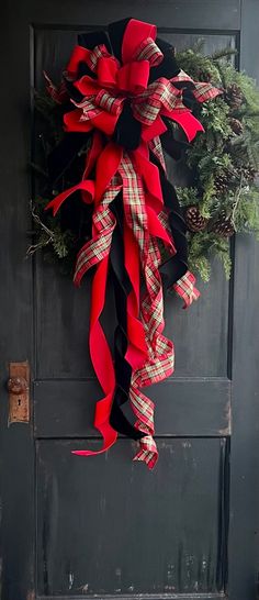 a red and black christmas wreath hanging on the front door