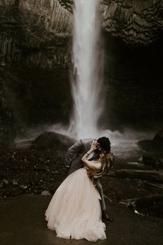 a bride and groom kissing in front of a waterfall during their elopement session