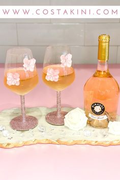 two wine glasses sitting on top of a pink counter next to a bottle of wine