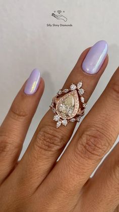 a woman's hand with purple nail polish and an oval shaped diamond ring on it