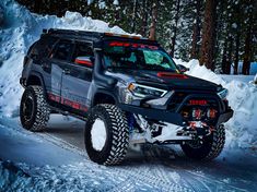 a black truck driving down a snow covered road