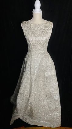 "Fabulous 1960's metallic silver and white Emma Domb formal dress with low back and high neckline. Zipper up the back and tulle under the skirt to help keep it full. Skirt near the hem has an orange spot about the size of a quarter Women's small/medium 36\" bust 27\" waist Open hips 60\" shoulder to hem" Vintage Silver Dress, White A-line Evening Dress For Gala, Fitted Full Skirt Evening Dress For Prom Season, Fitted Full Skirt Evening Dress For Prom, Elegant Fitted Vintage Prom Dress, Fitted Gown With Full Skirt For Prom Season, Fitted Full Skirt Gown For Prom Season, White A-line Vintage Dress For Party, White Glamorous Ball Gown Dress