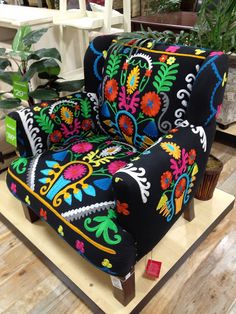 a colorful chair sitting on top of a wooden table next to a potted plant