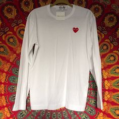 Cdg White Long Sleeve In Size Large (I Think It’s A Unisex Large But I’m Not Sure So Pls Refer To The Measurements) Chest- 19in Length- 28 In Sleeve Length- 21 In Shoulder- 7in Authentic Bought At The Play Cdg Store In Singapore In Prefect Condition With Tags Never Worn, Only Tried On Once White Shirt With Heart Graphic For Spring, White Relaxed Fit Tops With Heart Graphic, White Relaxed Fit Top With Heart Graphic, White Tops With Heart Graphic, Relaxed Fit, White Long Sleeve Tops With Heart Graphic, White Long Sleeve Top With Heart Graphic, Red Long Sleeve Top With Heart Graphic, White Long Sleeve T-shirt With Heart Graphic, Comme Des Garcons Sweatshirt