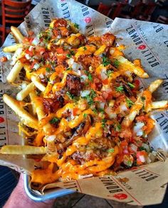 a basket filled with french fries covered in cheese and toppings