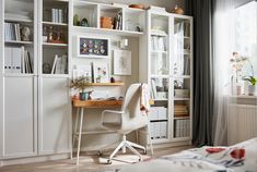 a white desk sitting in front of a book shelf filled with books and other items