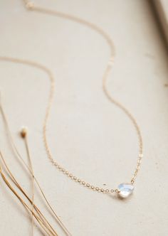 Subtle but stunning, this gorgeous cushion cut moonstone is the perfect addition to your jewelry collection. Attached to our most delicate cable chain, it can be worn alone but also pairs well with others. Stone measures approximately 8mm. Stone is wired wrapped to 15" of our delicate cable chain with a 1" extender. Available in 14kt Gold Fill + Sterling Silver. Kyra pairs it with our Milie Chain and Smiley Necklace. Handmade in Eau Claire, WI. Our jewelry is handmade so each piece will be uniqu Delicate Moonstone Necklace With Delicate Chain, Elegant Moonstone Necklace With Delicate Chain, Minimalist Moonstone Jewelry With Adjustable Chain, Delicate Moonstone Birthstone Jewelry, Gold Jewelry With Cushion Cut Birthstone, Gold Cushion Cut Birthstone Jewelry, Delicate Faceted 14k Gold Filled Jewelry, Dainty Wire Wrapped Moonstone Jewelry, Minimalist Wire Wrapped Moonstone Jewelry