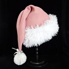 This festive Santa hat is made up in a soft mauve pink poly fleece fabric.  The hat is accented with a fluffy and soft white faux fur fabric turn up brim. Proportions of the hat are generous and will fit most head sizes, ladies or gents.    The styling is a slouch cone, traditional Santa look. Measurement for opening for your head is 24-25" circumference and the length is 20".  There is a fluffy white faux fur pompom accent stitched on the top accented with a silver ribbon bow and jingle bells. If you need more than the number of hats offered in this listing, just send me a message.  Customs quantities will depend on fabric availability at the time of your inquiry. Christmas Party Hat, Christmas Party Hats, Santa Claus Hat, Silver Ribbon, Pink Fleece, Fur Fabric, Christmas Celebration, Faux Fur Fabric, White Faux Fur