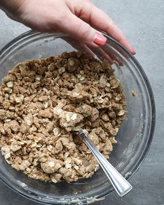 a bowl filled with oatmeal sitting on top of a table next to a person's hand