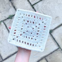 someone is holding up a crocheted square in their hand