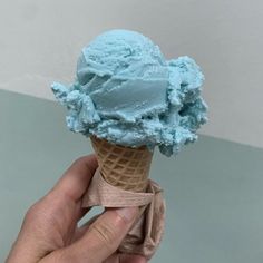 a hand holding an ice cream cone with blue icing