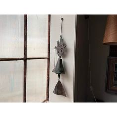 an old bell hanging on the wall next to a window with a lamp beside it