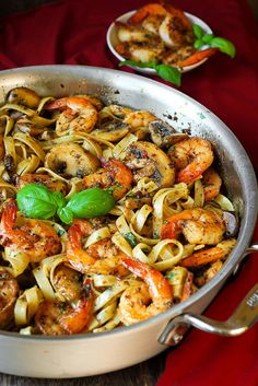 a pan filled with pasta and shrimp on top of a table