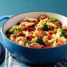 pasta with sausage, broccoli and tomatoes in a blue pan on a table