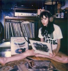 a young woman sitting on the floor with headphones and record player in front of her