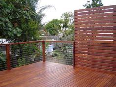 a wooden deck with metal railings and trees in the backgroung area