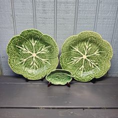 two green plates sitting next to each other on a wooden table in front of a gray wall