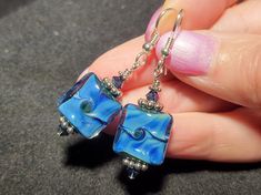 a pair of earrings with blue glass and silver beads hanging from it's earwires