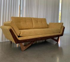 a couch sitting on top of a wooden frame in front of a curtained wall