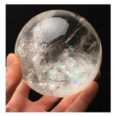 a person holding a crystal ball in their hand on a black background with white and silver flecks