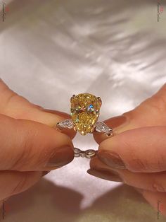 a woman's hand holding a fancy yellow diamond