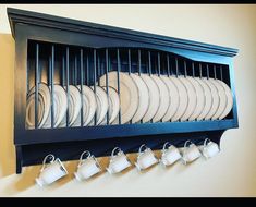 a rack with cups and saucers hanging on the wall next to a plate rack