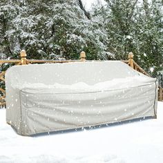 a covered bench sitting in the snow near trees