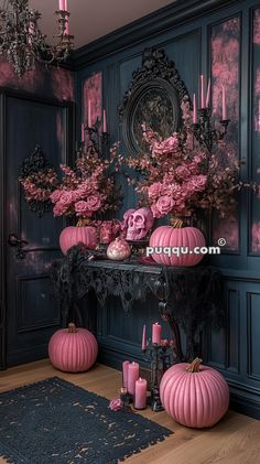 a table with pink flowers and candles on it in front of a blue painted wall