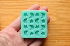 a hand holding a green cookie mold on top of a wooden table