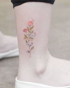 a small flower tattoo on the side of a woman's leg, with words below it