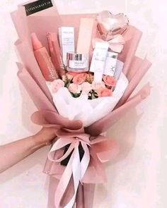 a person holding a bouquet of pink flowers and beauty products in it's hands