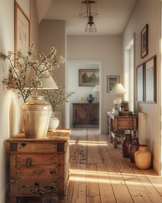 a vase with flowers sitting on top of a wooden table next to a lamp and pictures