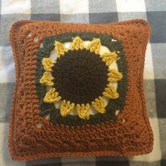 a crocheted sunflower pillow sitting on top of a checkered table cloth