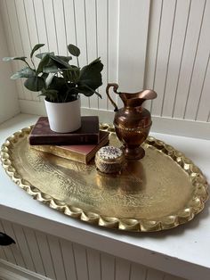 a gold tray with books and a potted plant on it