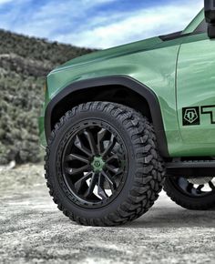 a green truck parked on top of a dirt field