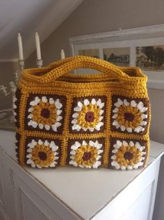 a yellow crocheted bag sitting on top of a white table next to a candle