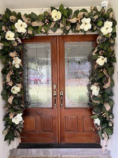 the front door is decorated with wreaths and flowers for an elegant touch to any home