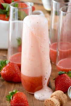 two glasses filled with liquid next to strawberries