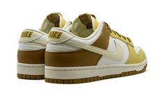 The Nike Dunk Low "Bronzine" is a colorway of the classic sneaker with light and dark gold accents.  The Dunk Low “Bronzine” features a white leather base and Bronzine and Saturn Gold leather panels.  A Coconut Milk leather Swoosh is seen on both sides, while “Nike” detailing is embroidered on the heel and printed on the tongue tag above a Swoosh.  The Sail rubber midsole gives the shoe a vintage look. Nike Dunk Low Bone Tan, Nike Custom Gold Low-top Sneakers, Light Chocolate Nike Dunks, Nike Dunk Low Light Orewood Brown, Nike Dunk Low Off-white University Gold, Light Sneakers, Nike Dunk Low, Dark Gold, Stadium Goods