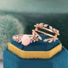 a pink opal ring sitting on top of a blue velvet hat with gold trim