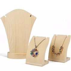 three pieces of jewelry are on display in front of a wooden stand with two necklaces